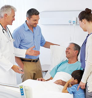 A senior man being visited by his sfamily in hospital